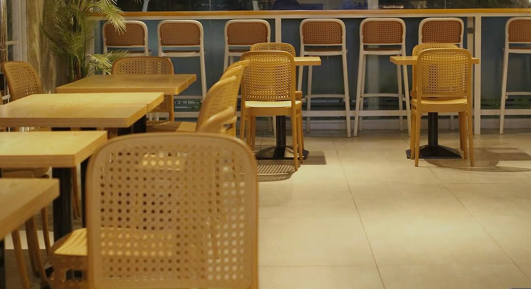 Happy Valley Café dining area — rows of rattan chairs along the window counter, warm evening light